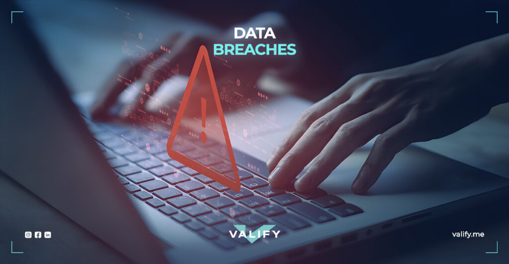 A laptop and a hand writing on it with a danger sign and a tov reading 'Data Breaches'
